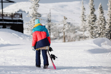 Woman snowboarder walks on the snowy mountain