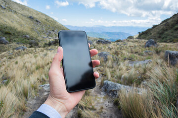 Man holding a mobile phone in a mountain cime