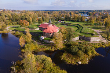 Naklejka na ściany i meble Aerial view of ancient fortress Korela in priosersk with river and park in golden autumn, red and orange colours