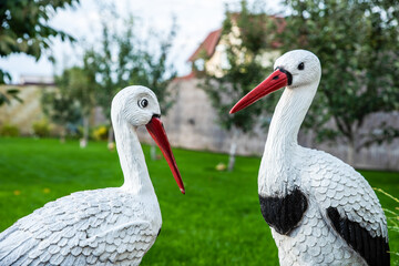 Outdoor decorations for home courtyard or parks. Decorative elements for home garden. Handmade figures of wild crane birds. Two artificial colored statues in the backyard. Landscape design at home.