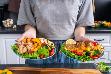 Woman holding plates with vegetables and fish cooked on home grill.