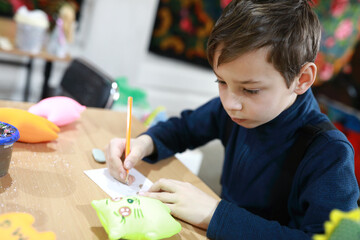 Boy drawing soft toy design on sheet of paper