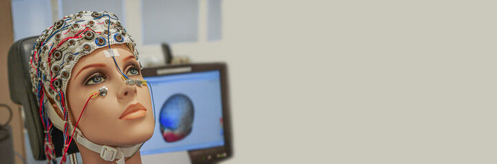 Beautiful woman manikin with EEG hat in experimental recording of brain activity shown in computer...