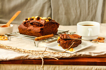 Chocolate cake and slice Spoon with tasty chocolate cream and nuts on on a linen cloth background.Cup of coffee and dessert concept