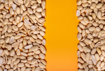 Peeled peanuts on a yellow background with free space in the middle of the strip