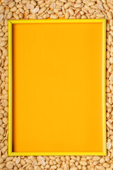 Peanut frame with free space. View from above. Yellow bright background.