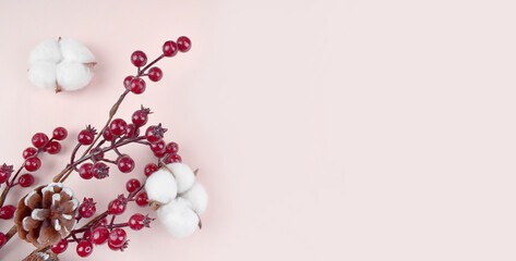 Happy Christmas composition with red berries and cotton flowers on pastel background. Greeting minimalist concept for winter holidays. New year 2021. Banner.