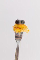 Close up of pancake and berries with dripping honey on fork on white background