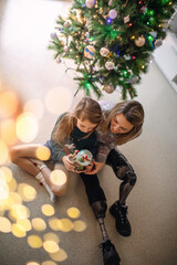 Disabled woman and her daughter sit with Christmas balls and wait for Santa Klaus.