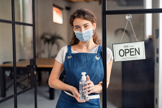 Waitress holding bottle of sanitizer at business entrance