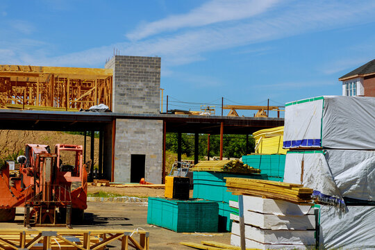 A woodentruss being lifted by a boom truck forklift in the building materials a stack of boards wood frame a new home