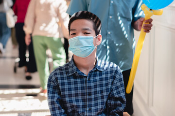 Fototapeta na wymiar Asian special child on wheelchair wearing protection mask against PM 2.5 air pollution and flu Covid 19,Coronavirus on department store background, N95 to prevent the spread of the virus disease 2020.
