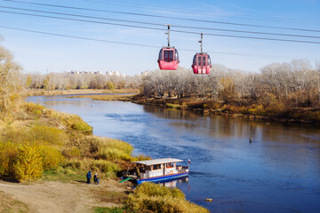Ural river, Orenburg, Russia - October, 18, 2020: Cable car and pleasure boat near the river bank