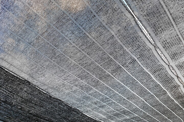 Low angle view black shading net pattern texture and background. Weaved plastic shade to protect and avoid direct sunlight to the plants.