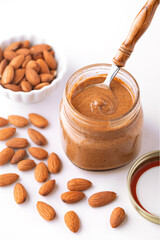 Fresh almond butter in a small glass jar with raw almonds