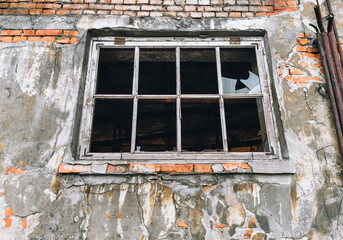 Brick wall with a broken window without glass and a wooden frame. An abandoned deserted old...