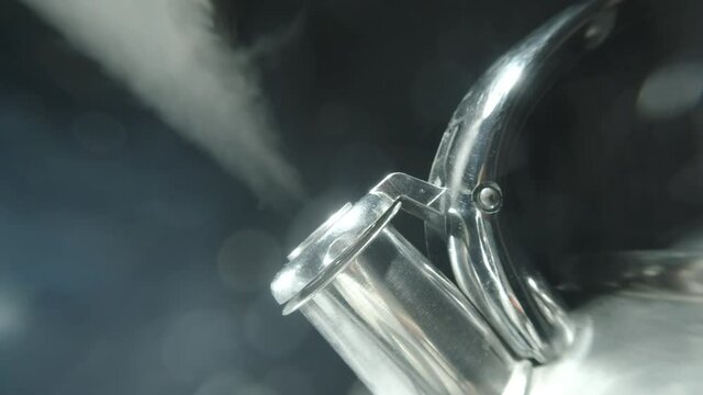 4k macro raw video of kettle whistling, boiling kettle with steam texture on a beautiful bokeh black background.
