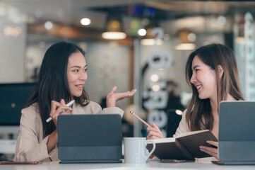 two smiling businesswomen working with laptop in office