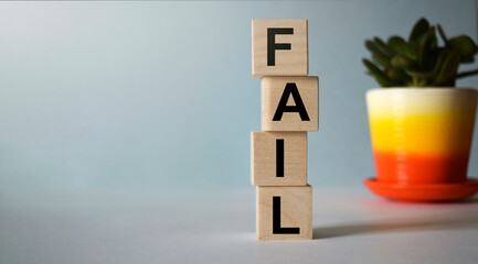 The inscription FAIL on wooden cubes isolated on a blue background, the concept of business and finance.