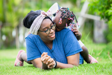 Cheerful african american girl playing on the back of her mother, Happy mother and daughter laughing together outdoor