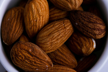 Almonds in a white bowl isolated in a white background close up.