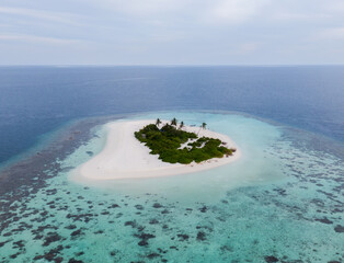 tropical island palm fringed an uninhabited in middle of indian ocean (drone aerial)