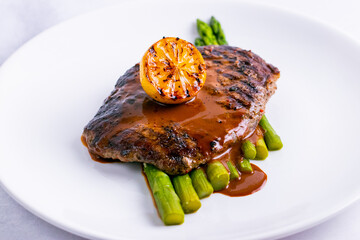 Tenderloin steak with lemon isolated in white plate close up.