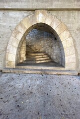 Fototapeta na wymiar Stone Arch In Wall Over Stairs Leading Up