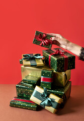 A woman's hand reaches for a gift. Mountains Of Gifts. New Year Sales. Christmas giftboxes with red...