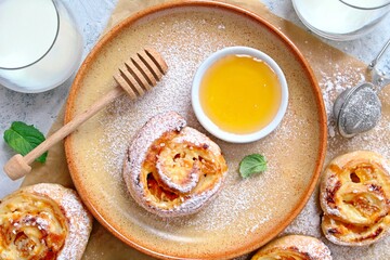 Sweet puff pastry roll for breakfast or snack served with honey and milk. Top view with copy space. Healthy food.