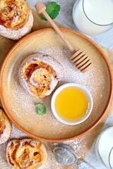 Sweet puff pastry roll for breakfast or snack served with honey and milk. Rolls with crema cheese and peaches. Healthy breakfast or snack for children.