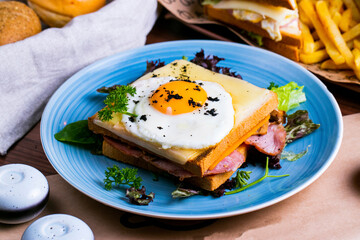 French croque madame in a blue ceramic plate on a table with food.