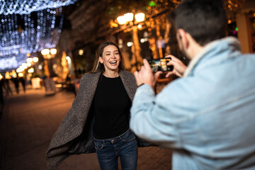 Young smiling couple having fun during the winter holidays on the street.