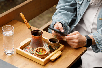 Fototapeta na wymiar smartphone in female hands on the table with Turkish coffee and sweets. High quality photo