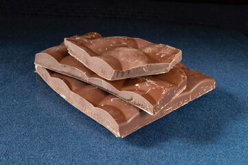 Piece of dark chocolate rests upon turn blue table