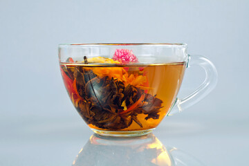 Exotic green flower bud tea in a glass cup on a gray background.