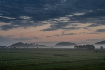 mountains with fog in the background and a field of grass and clouds