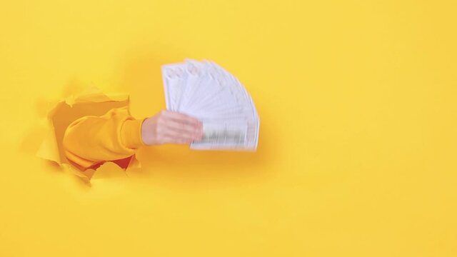 Close up win woman hand arm hold fan of cash money in dollar banknotes isolated through torn yellow background studio Copy space advertisement place for text image Advertising area workspace mock up