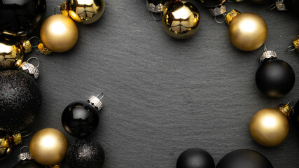 Winter design. Gold Christmas baubles decoration on black textured background with copy space. Flat lay, top view.