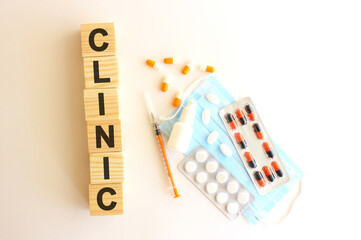 The word CLINIC is made of wooden cubes on a white background. Medical concept.
