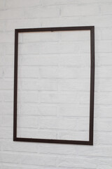 Empty blank frame on a white brick wall