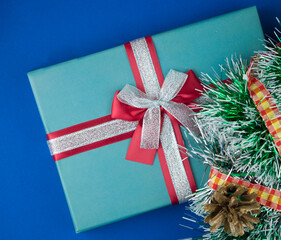 Christmas gift box with decoration on a dark blue  background, top view, copy space.