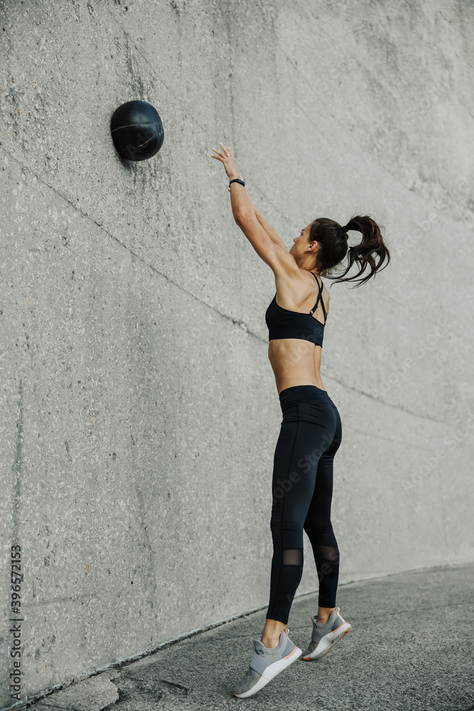 Wall mural female athlete exercising with a medicine ball