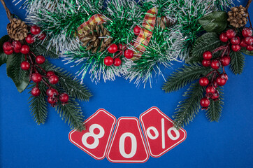 Big sales 80%, eighty percents with Christmas wreath on a dark blue  background, top view, copy space, flat layout. Christmas big sale.