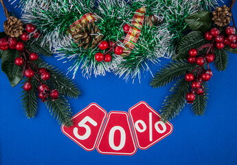 Big sales 50%, fifty percents with Christmas wreath on a dark blue  background, top view, copy space, flat layout. Christmas big sale.