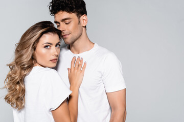  couple in white t-shirts posing isolated on grey