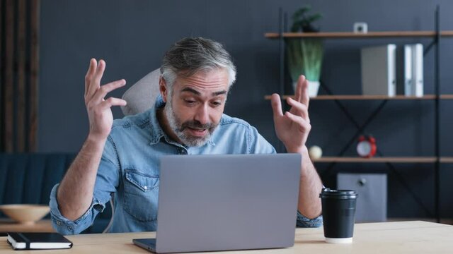 Serious Angry Nervous Successful Businessman having some Problems swears with Employees. Mature Businessman Boss Leader is holding Online Conference, Webinar, Seminar. Man yells and waves his Hands.