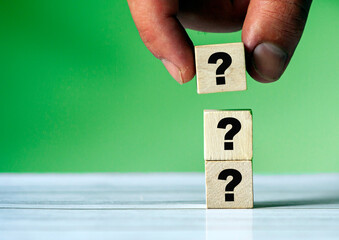 Question mark on wooden block with human hand or finger. New idea and inspiration. Quiz and support...