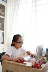 Obraz na płótnie Canvas Portrait of 11-year-old teenager Asian girl using laptop for online study during homeschooling at home