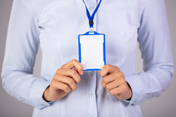Woman holding Identification white blank plastic id card. Young woman holding a mock-up blank business card and smiling. Woman wear blank vertical ID badge mockup, stand isolated.